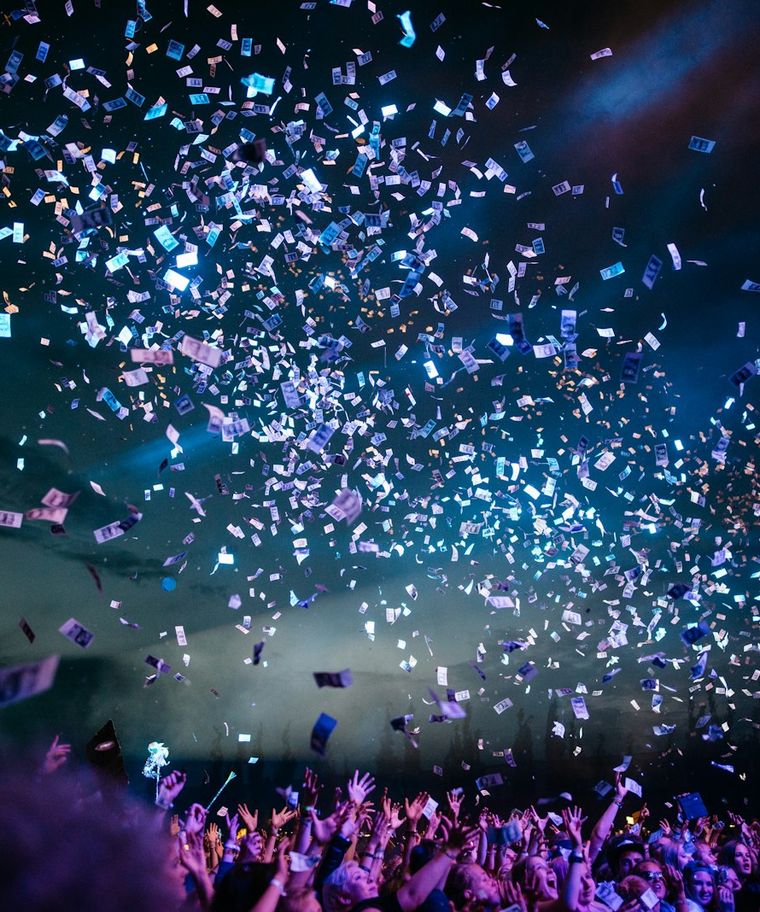 Blue and white lighting over a celebrating crowd as confetti falls